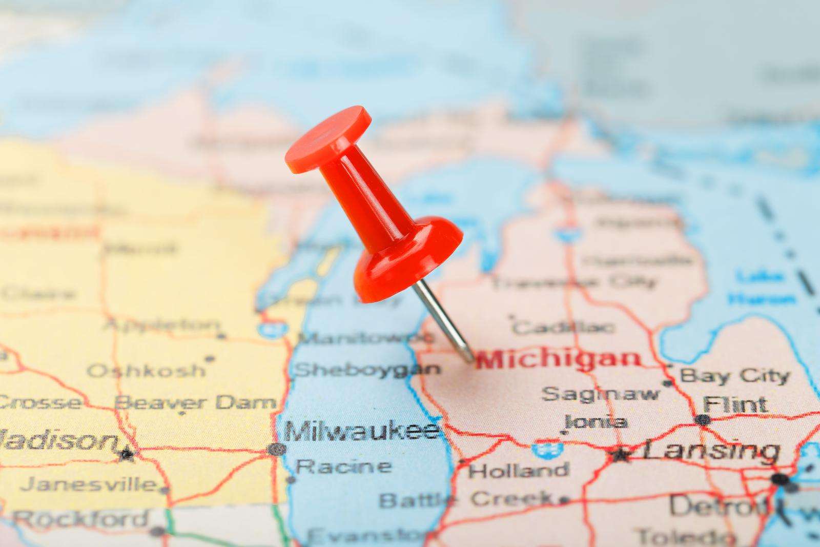 Red clerical needle on a map of USA, Michigan and the capital Lansing. Close up map of Michigan with red tack.