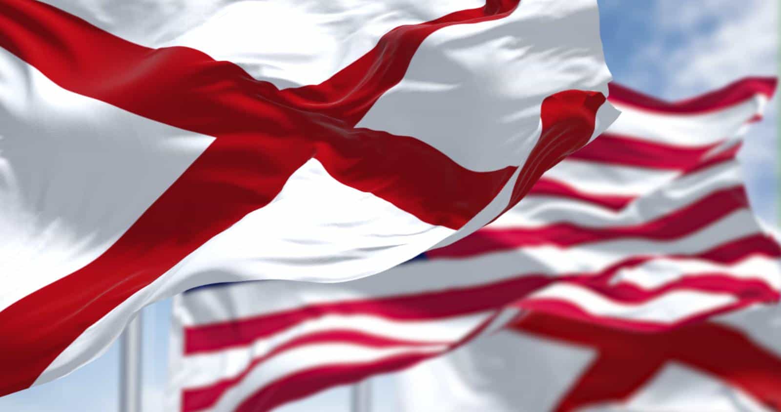 The flags of the Alabama state and United States of America waving in the wind. Alabama is a state in the Southeastern region of the United States. Democracy and independence. American state.